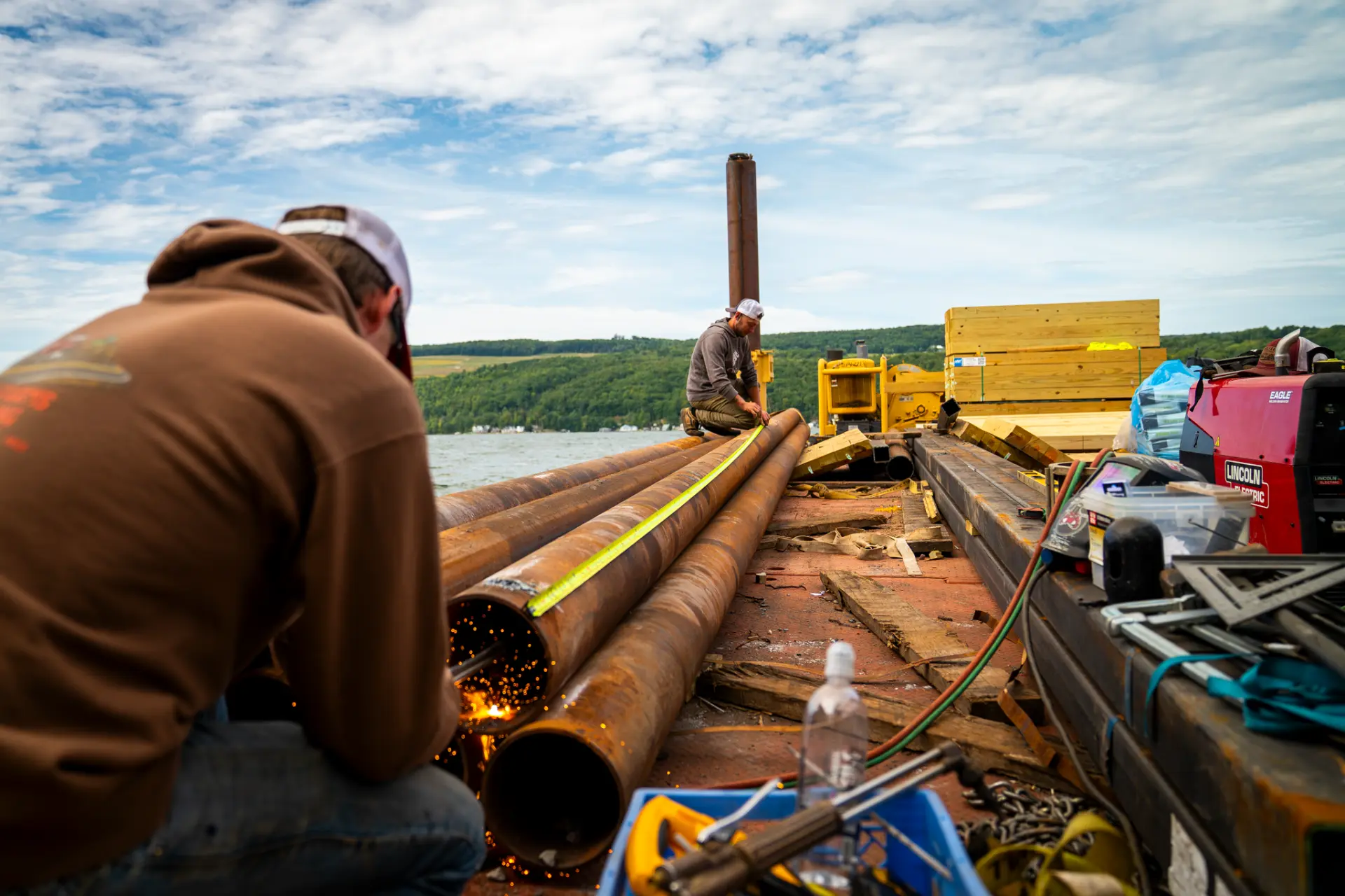 Crew measuring steel pilings on a work barge